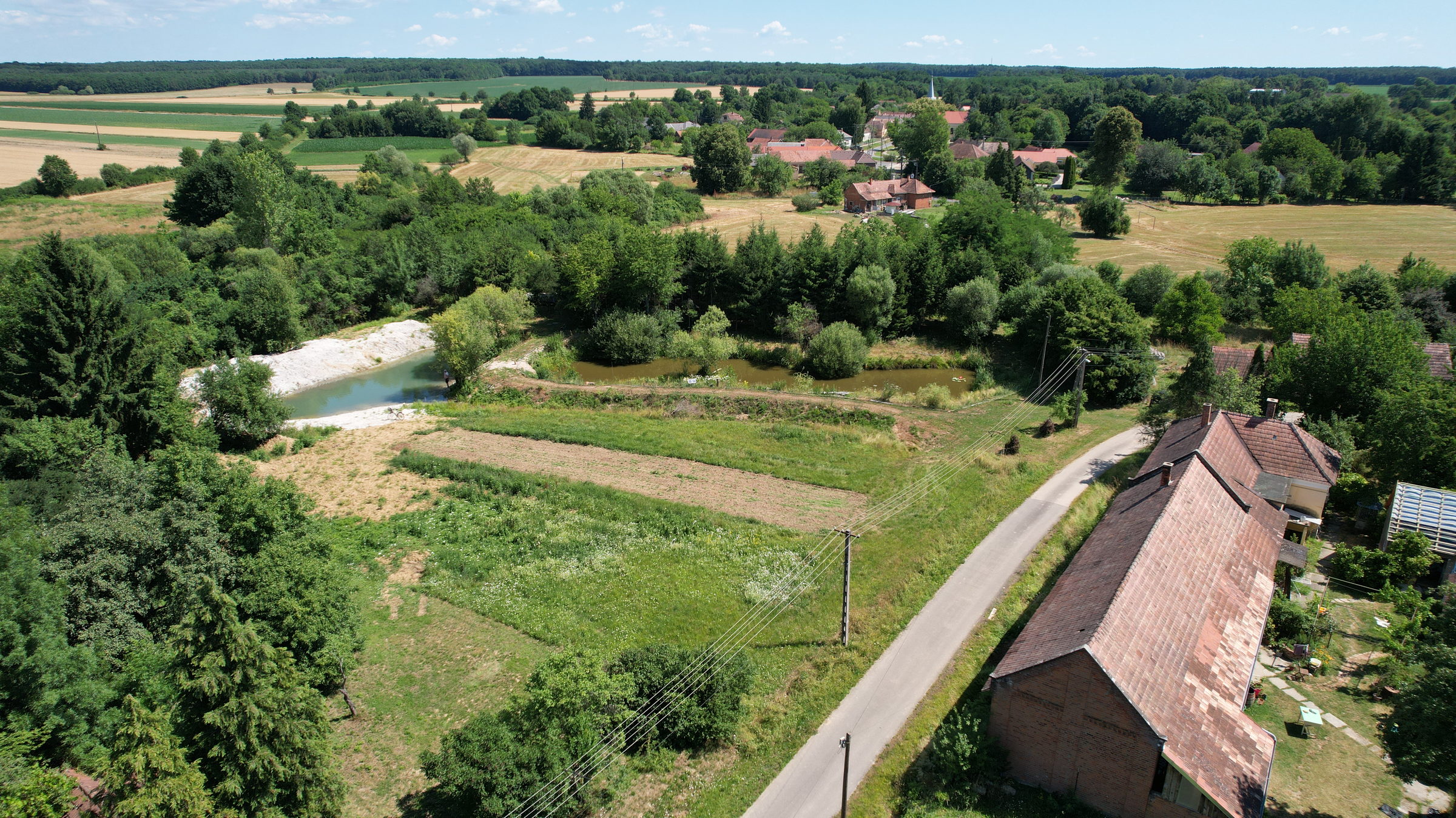 Kerkakutas látképe kertekkel, tóval és a falu felé vezető úttal